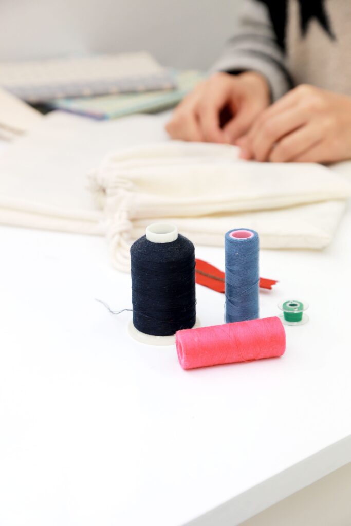 image of person sewing with multiple rolls of thread on the table