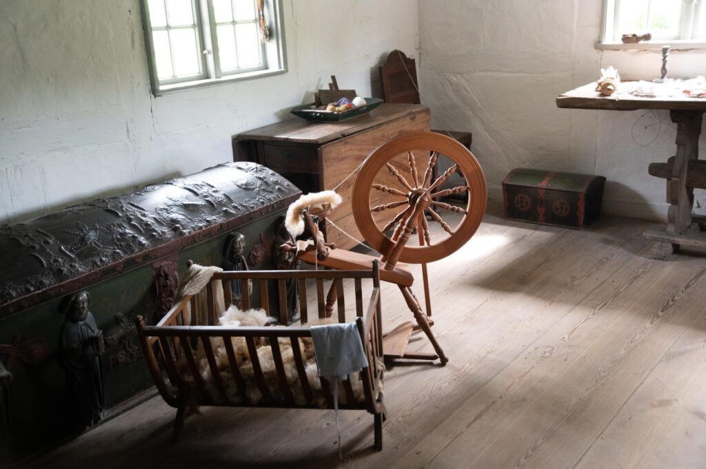 spinning wheel in vintage room near a chest 