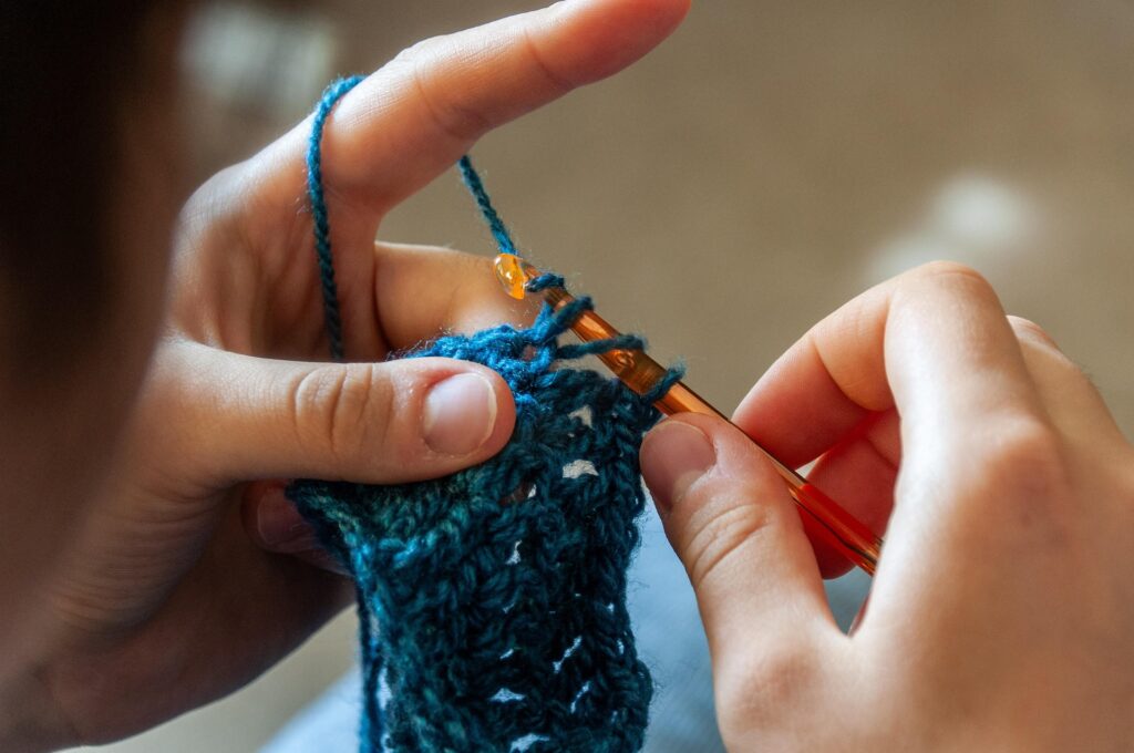 a person crocheting with blue yarn 