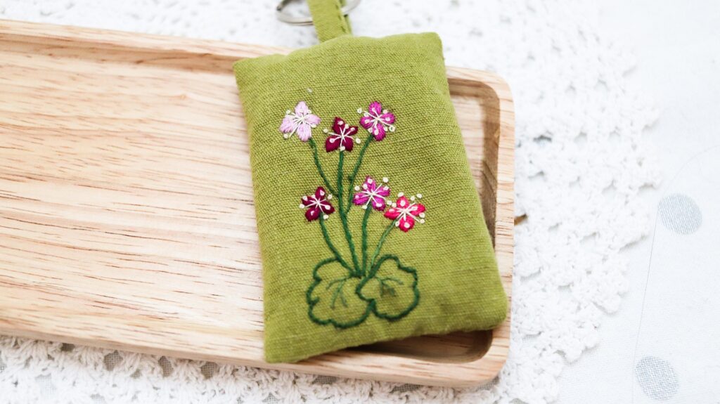 A needlepoint piece with flowers on it resting on a wooden tray