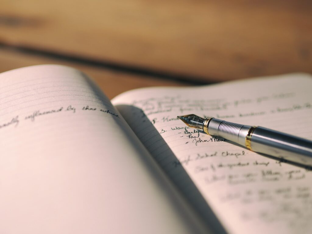 A journal with cursive writing and a fountain pen sitting on the journal