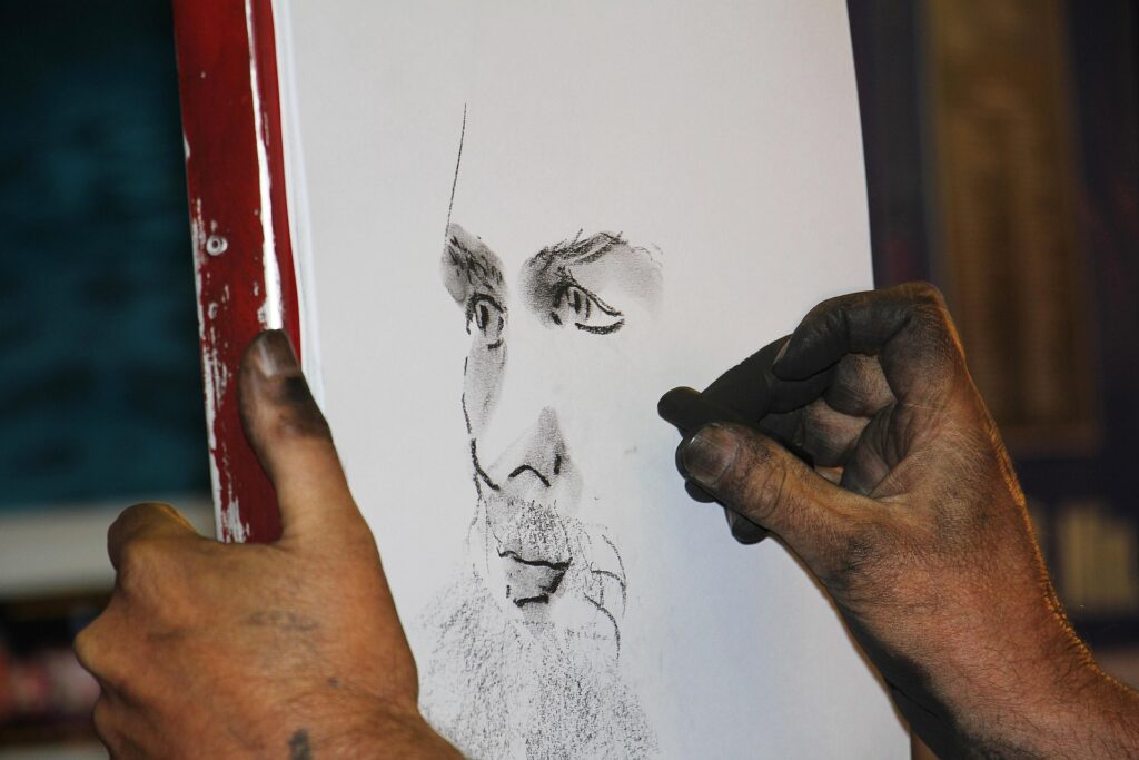 Somebody drawing a picture of a man with a stick of charcoal