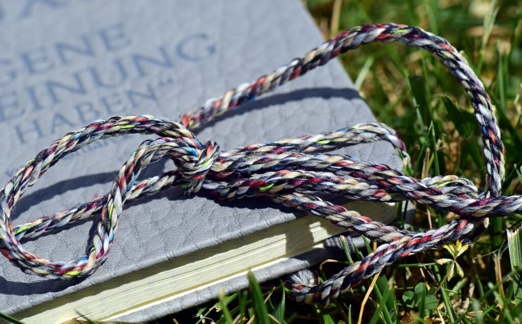 Light gray book with a multicolor rope resting on it