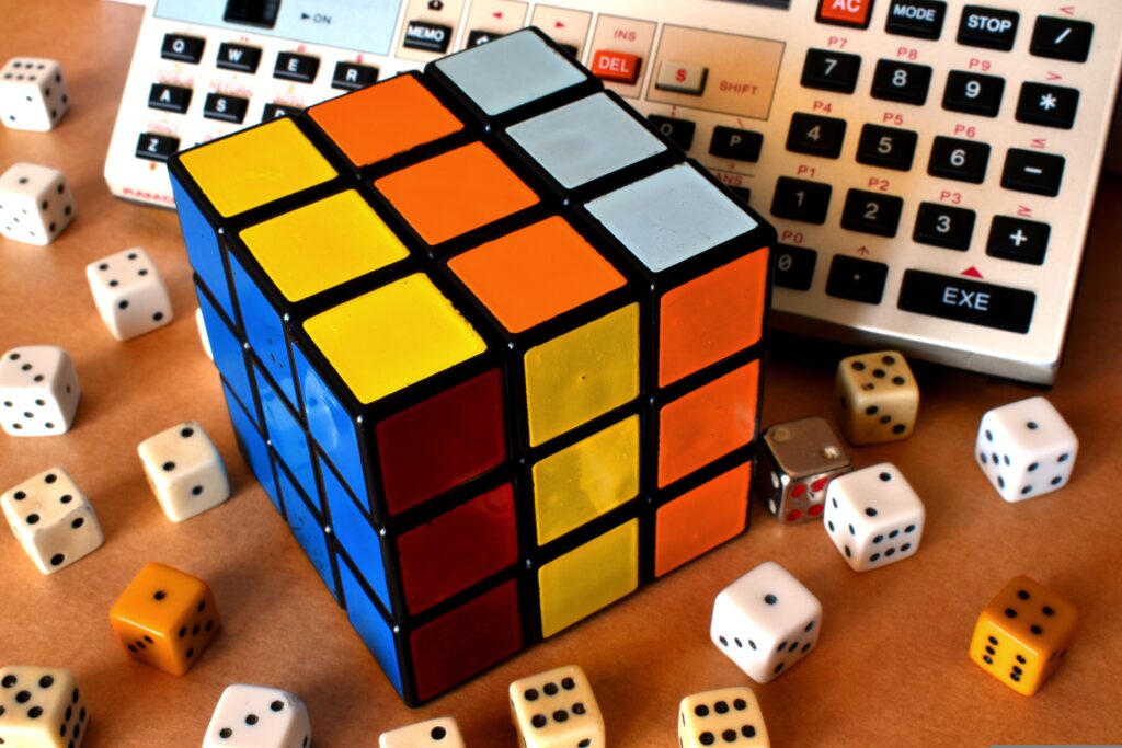 A Rubik's cube and dice in front of a calculator